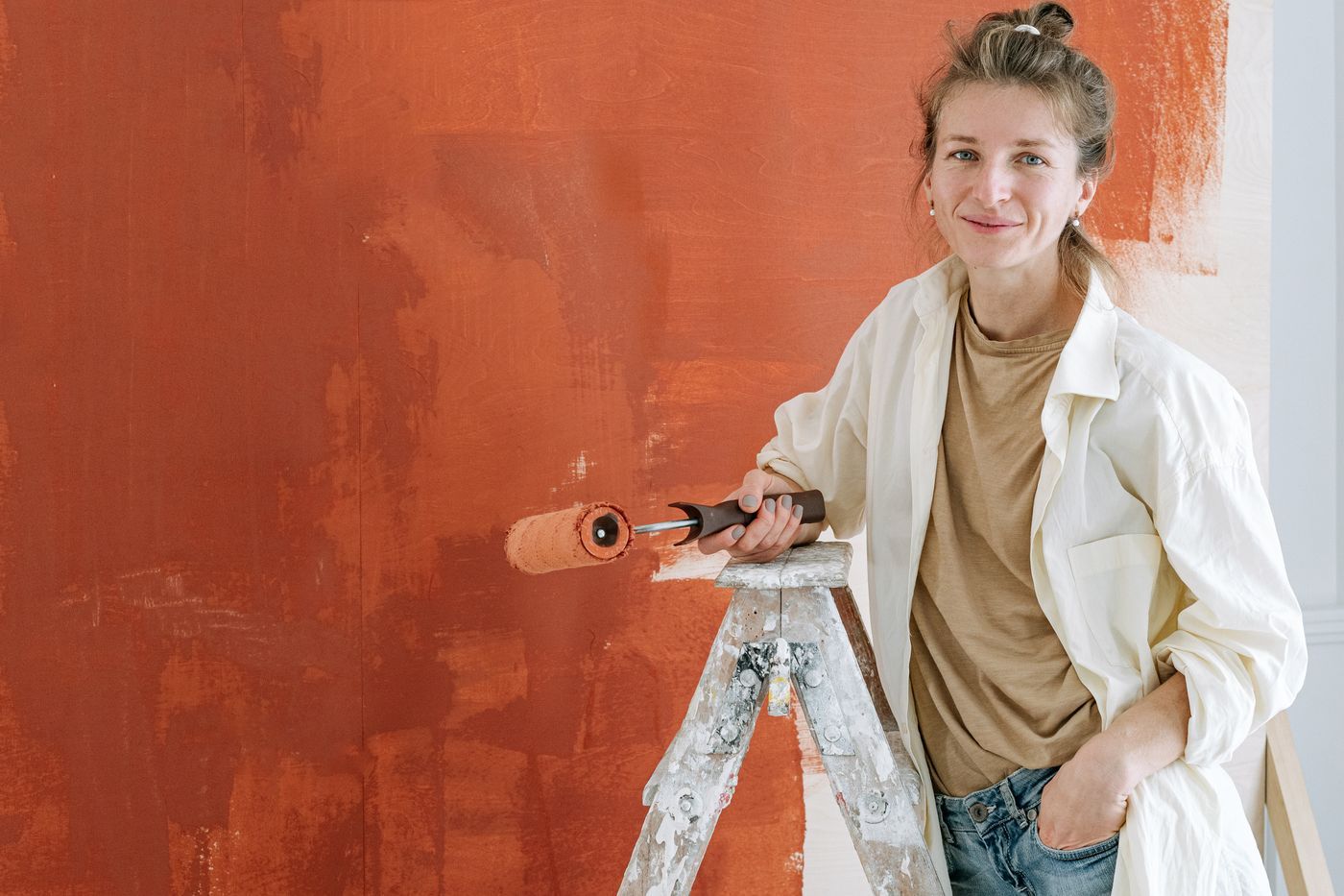 Vrouw met verfroller voor een terracotta geverfde muur